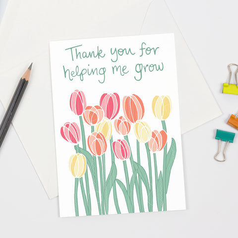 A floral themed gratitude greeting card that is perfect to give to mothers, teachers, and more - featuring colorful orange, pink, and yellow tulips against a white background with green handlettered text (above flowers) that says "Thank you for helping me grow". Perfect for Step-mothers, foster moms, grandmothers, teachers, moms, and more!