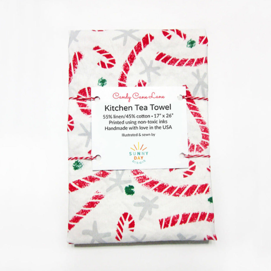 https://cdn.shopify.com/s/files/1/0430/4057/1556/products/Candy-Cane-Lane-Kitchen-Tea-Towel-Packaged-Sunny-Day-Designs-LowRes_1d81e233-e5cb-4435-8f23-7754fd45c2aa_1024x1024.jpg?v=1669343330