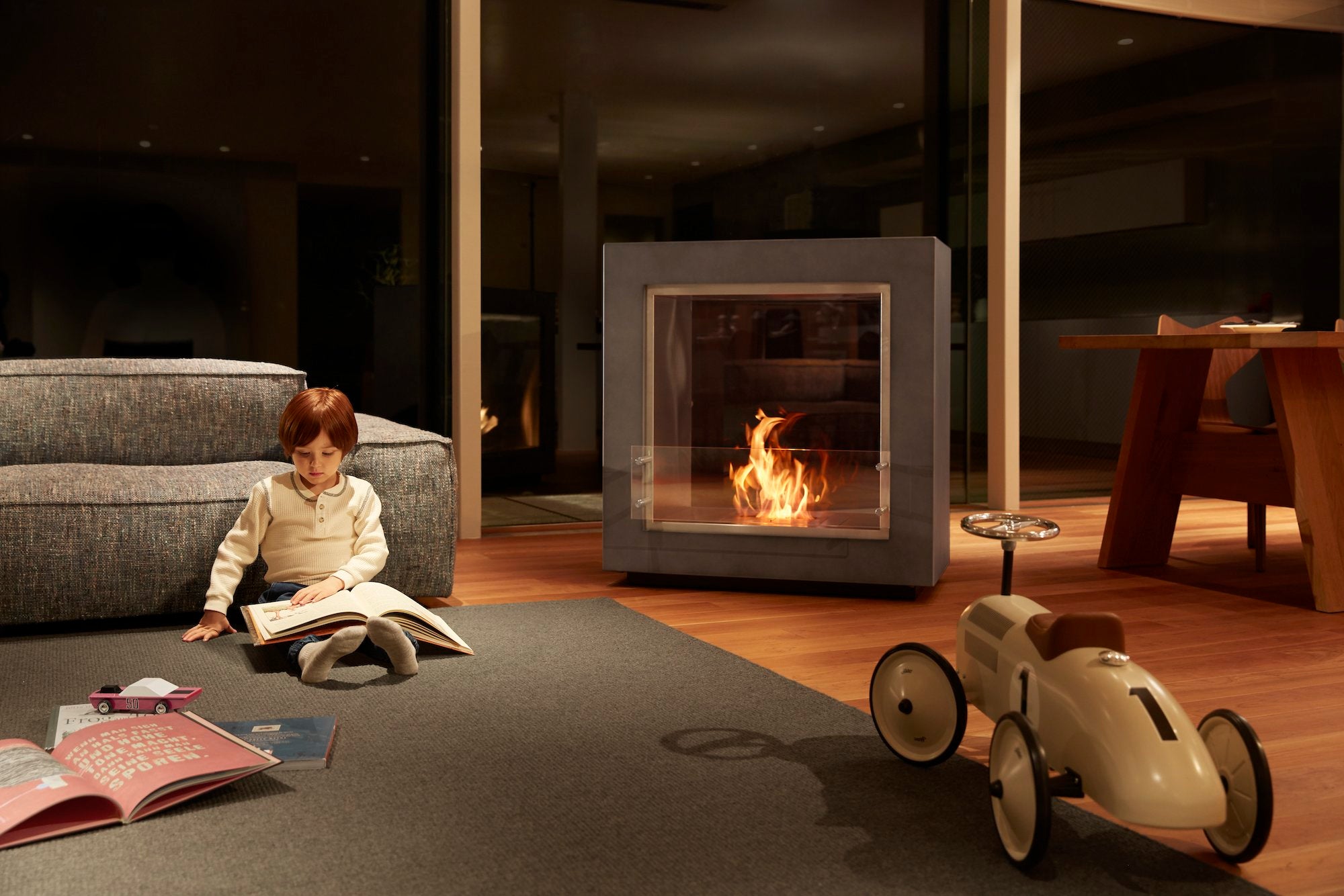 バイオエタノール暖炉「EcoSmart Fire」製品のFUSION STANDARD COLORをリビングに置き子どもが温まっている画像。暖炉と違って工事が不要なため、自由な場所に配置できています。