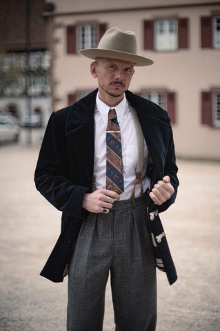 Men dressed in vintage style. Navy blue corduroy jacket, hat, pants and shirt. Tie and suspenders. 