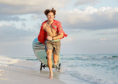 Paddle board wheels carried on the beach by man