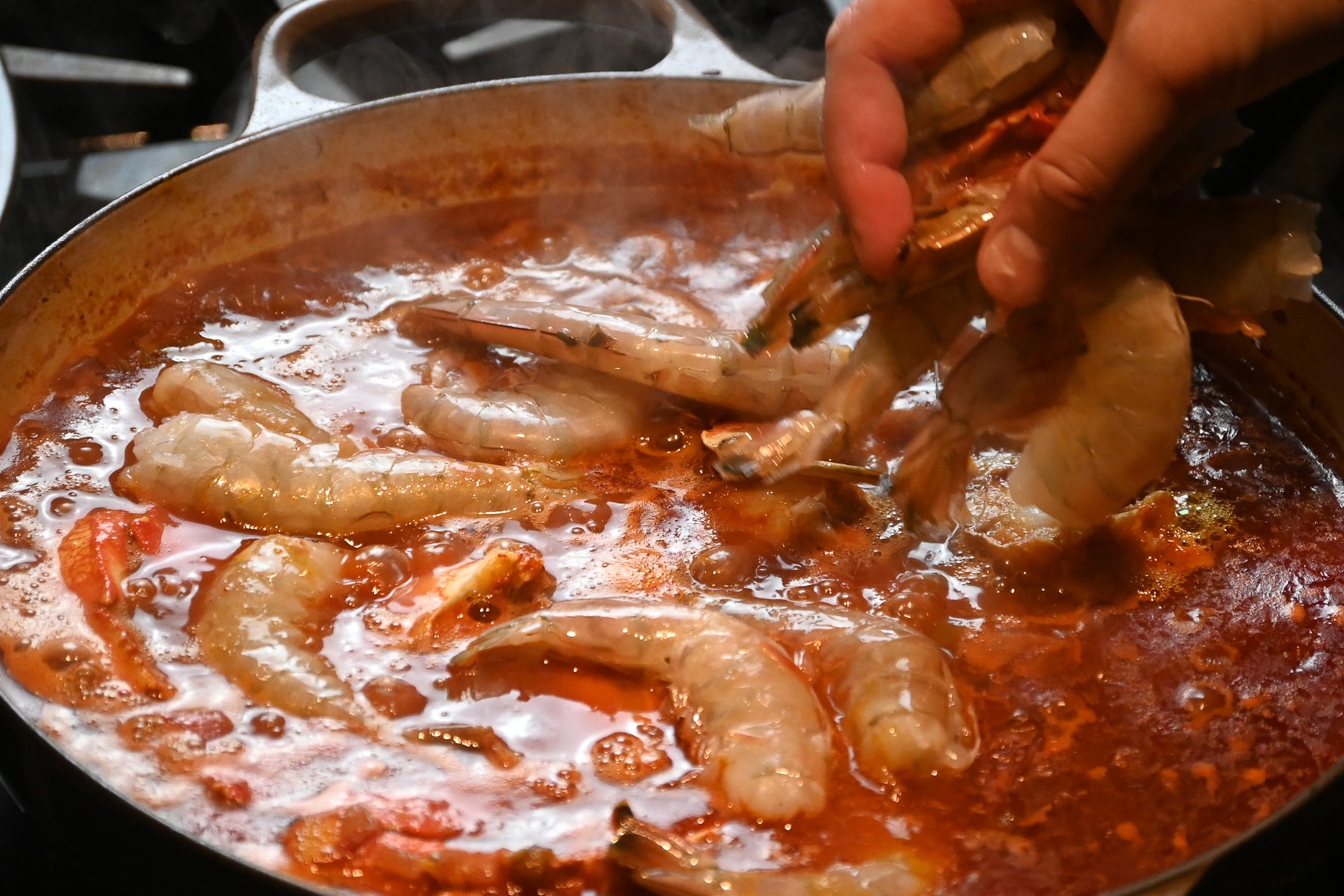 chef adding shrimp to cioppino