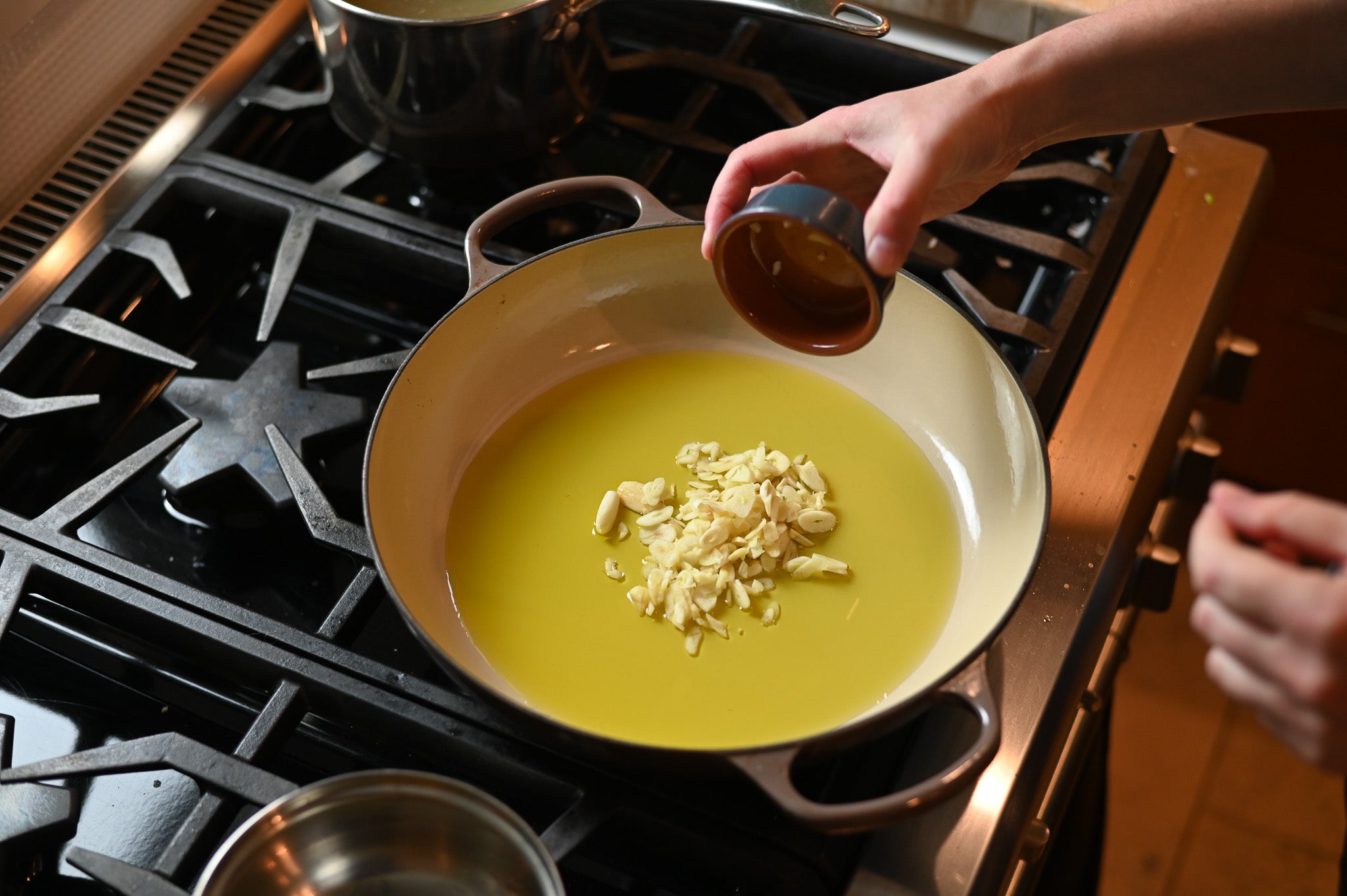 heating oil in a pan with garlic on the stovetop