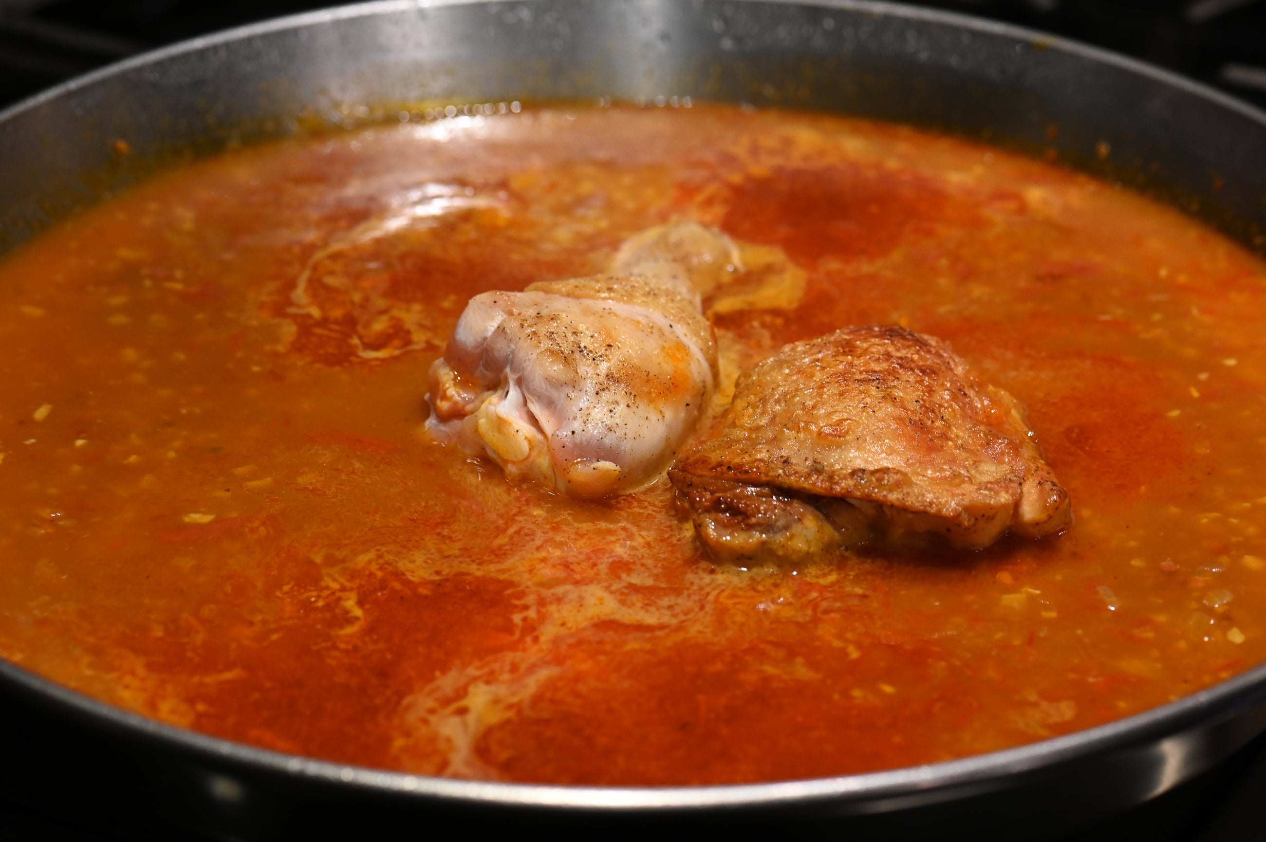 adding chicken high and leg to the paella pan