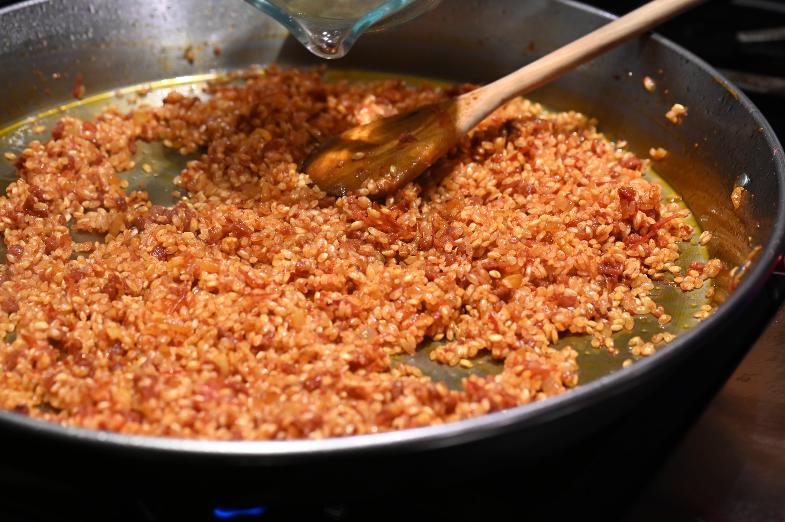 adding white wine to the paella pan