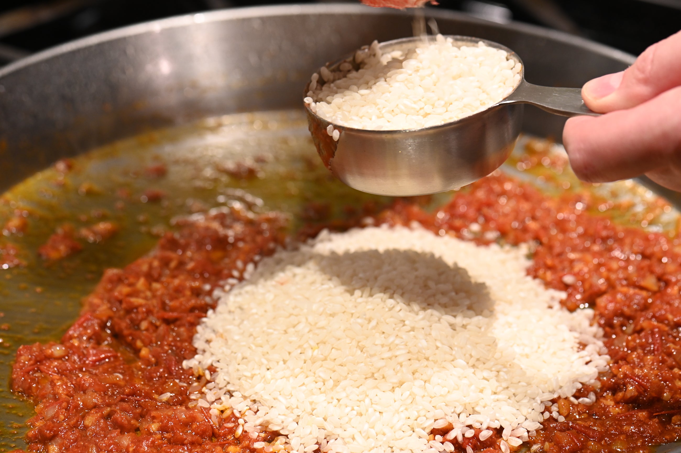 adding rice to the paella pan