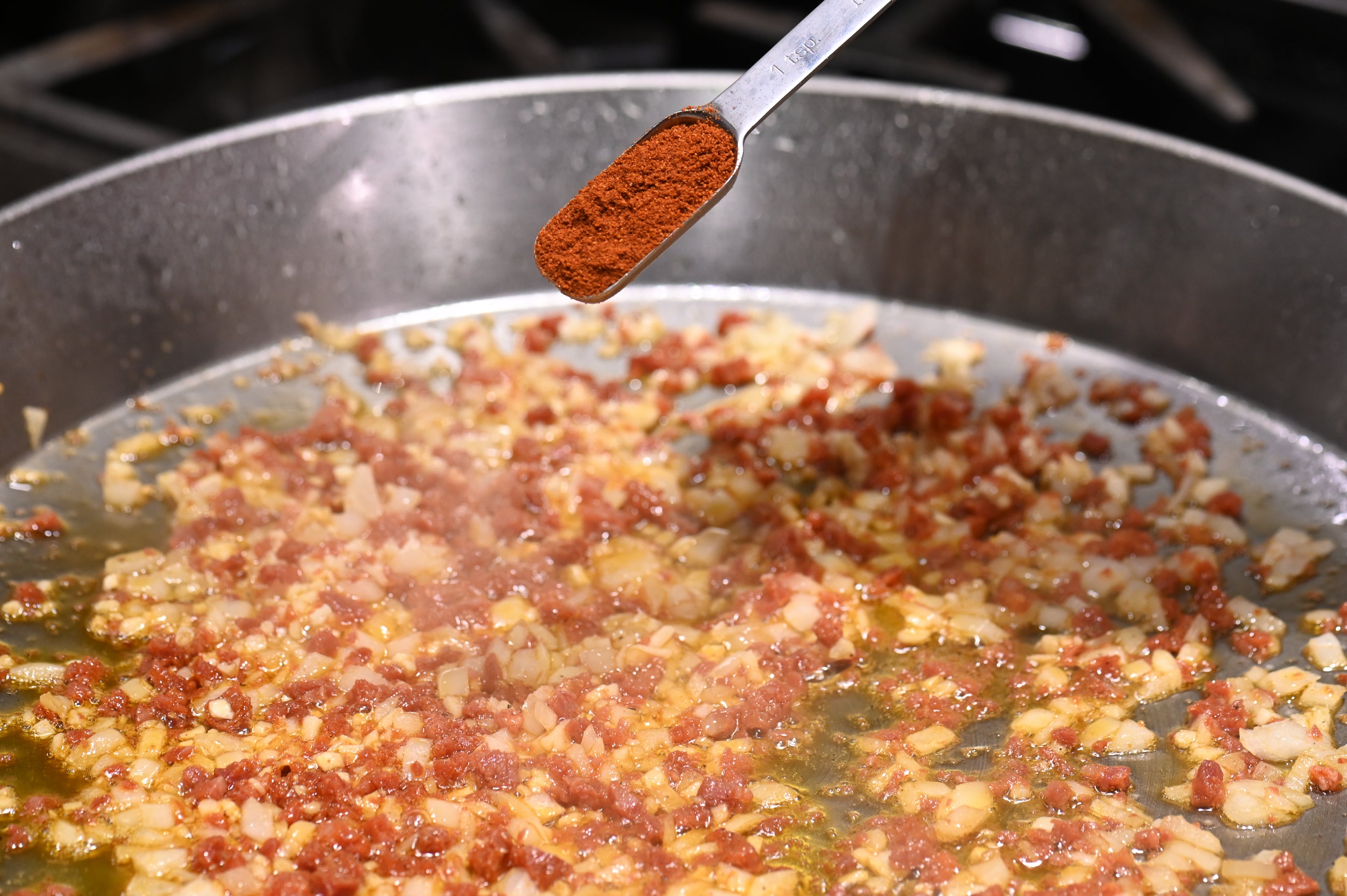 sprinkling paprika on paella pan