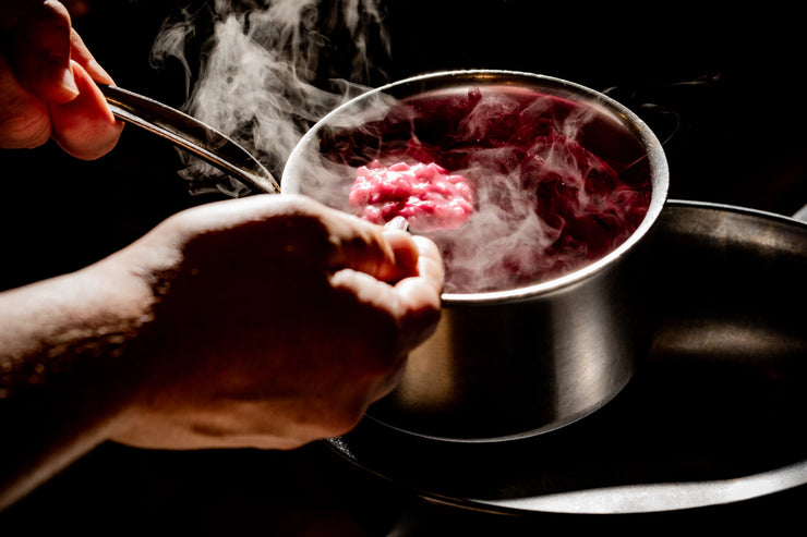 chef hands spooning pink risotto
