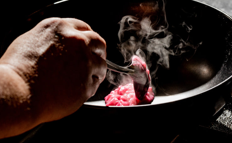 chef hands plating pink risotto