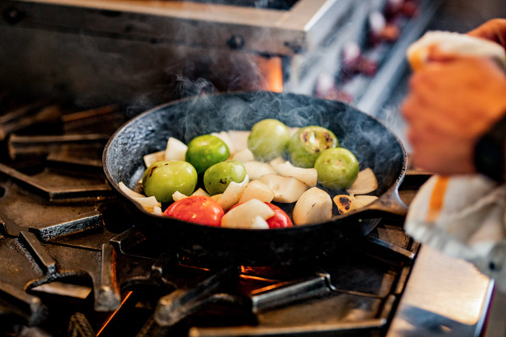 Tomatillos cooking in cast-iron pan with onion