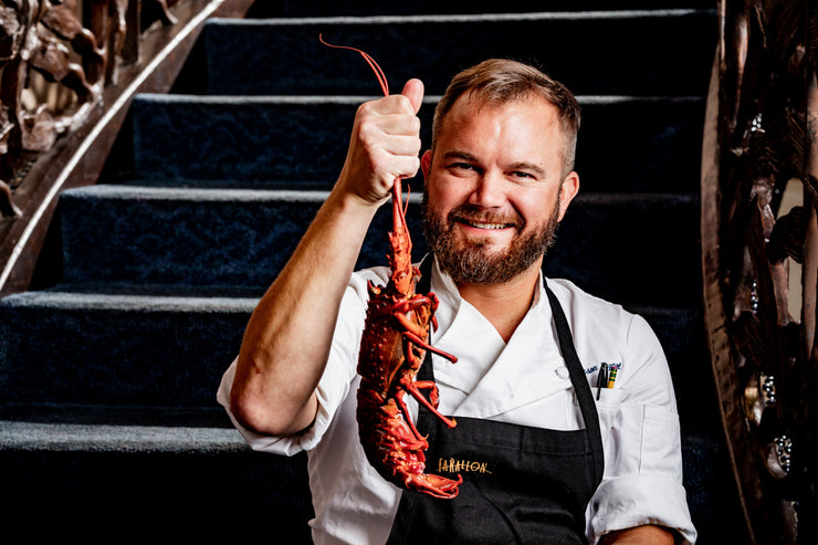 Chef holding spiny lobster by stairway