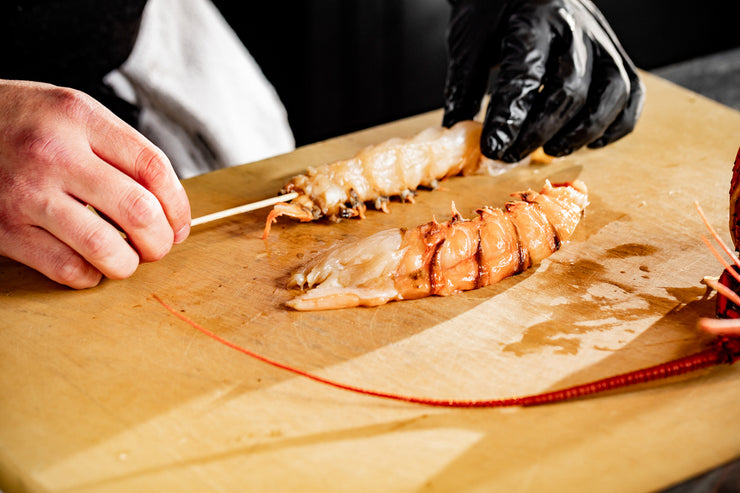chef hands skewer spiny lobster tails