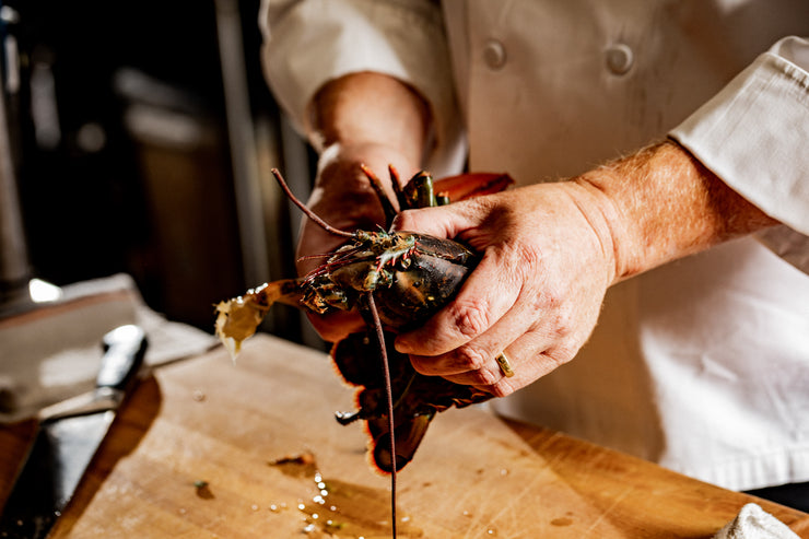 chef hands separating lobster claws from the body