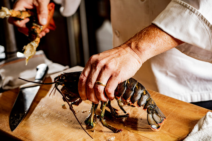 chef hands holding lobster while setting aside claws