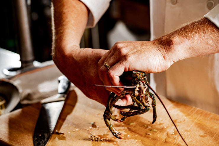 chef hands separating lobster body from lobster head