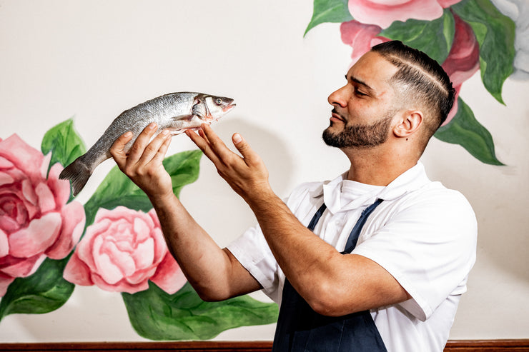 Chef examining fish in front of flower wallpaper