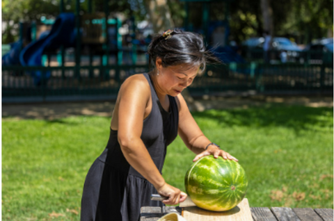 Woman cutting watermelon outside