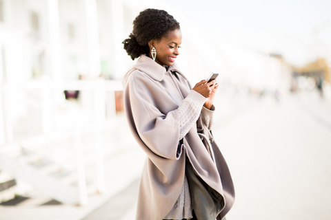 Woman smiling while looking down at her phone.