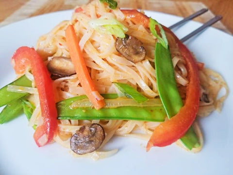 Thai red curry noodles with vegetables on a plate with chopsticks