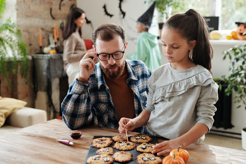 Father and daughter decorating Halloween cookies