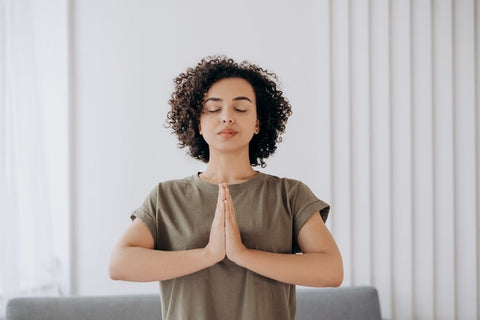 Woman meditating with eyes closed and hands together at heart.