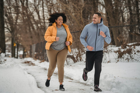 Man and woman running in the winter on a path.