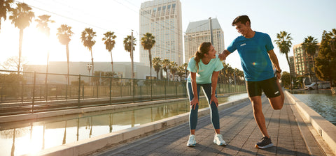 Woman helping Man stretch on a run wearing Hoka Running Shoes