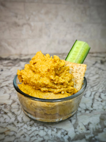 small jar of hummus with crackers and veggies