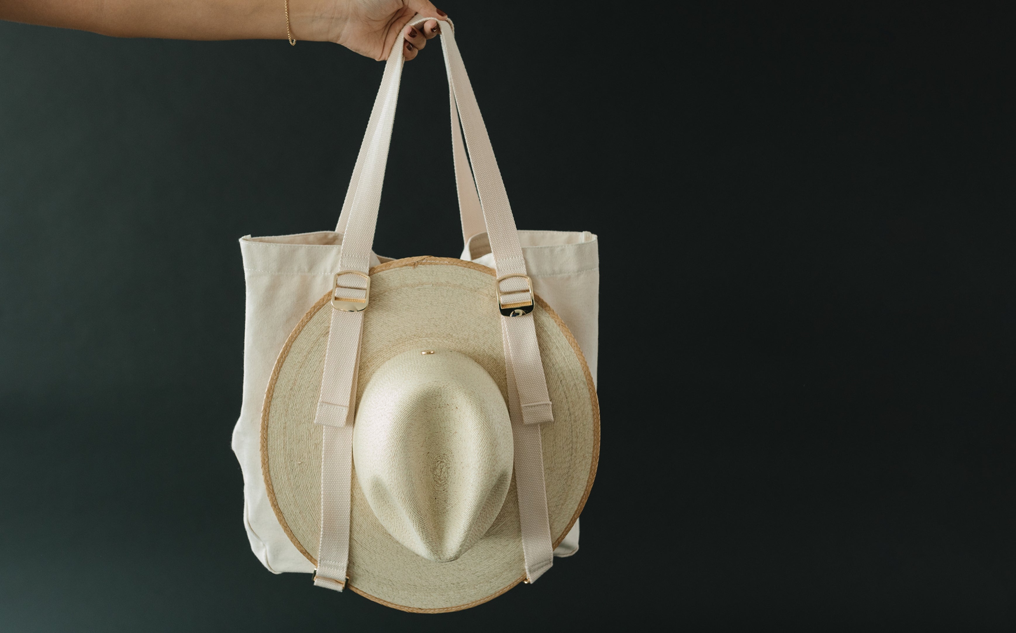 canvas hat carrying tote with a straw hat attached to the outside