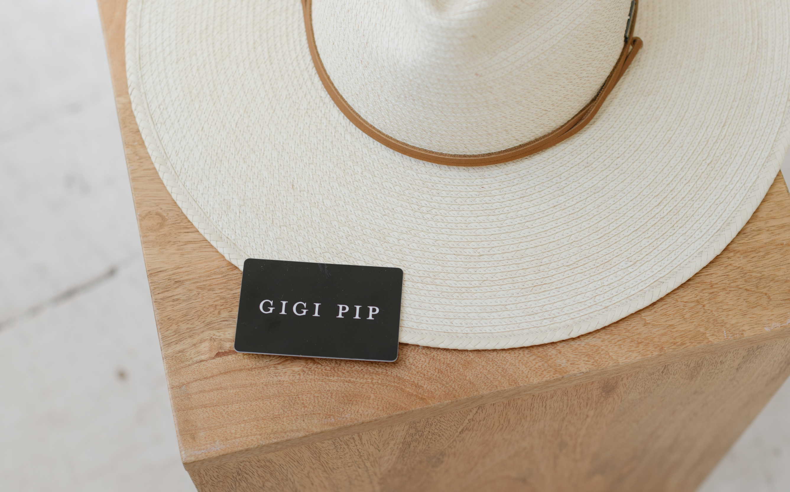 A gift card laying flat on top of an ivory straw hat