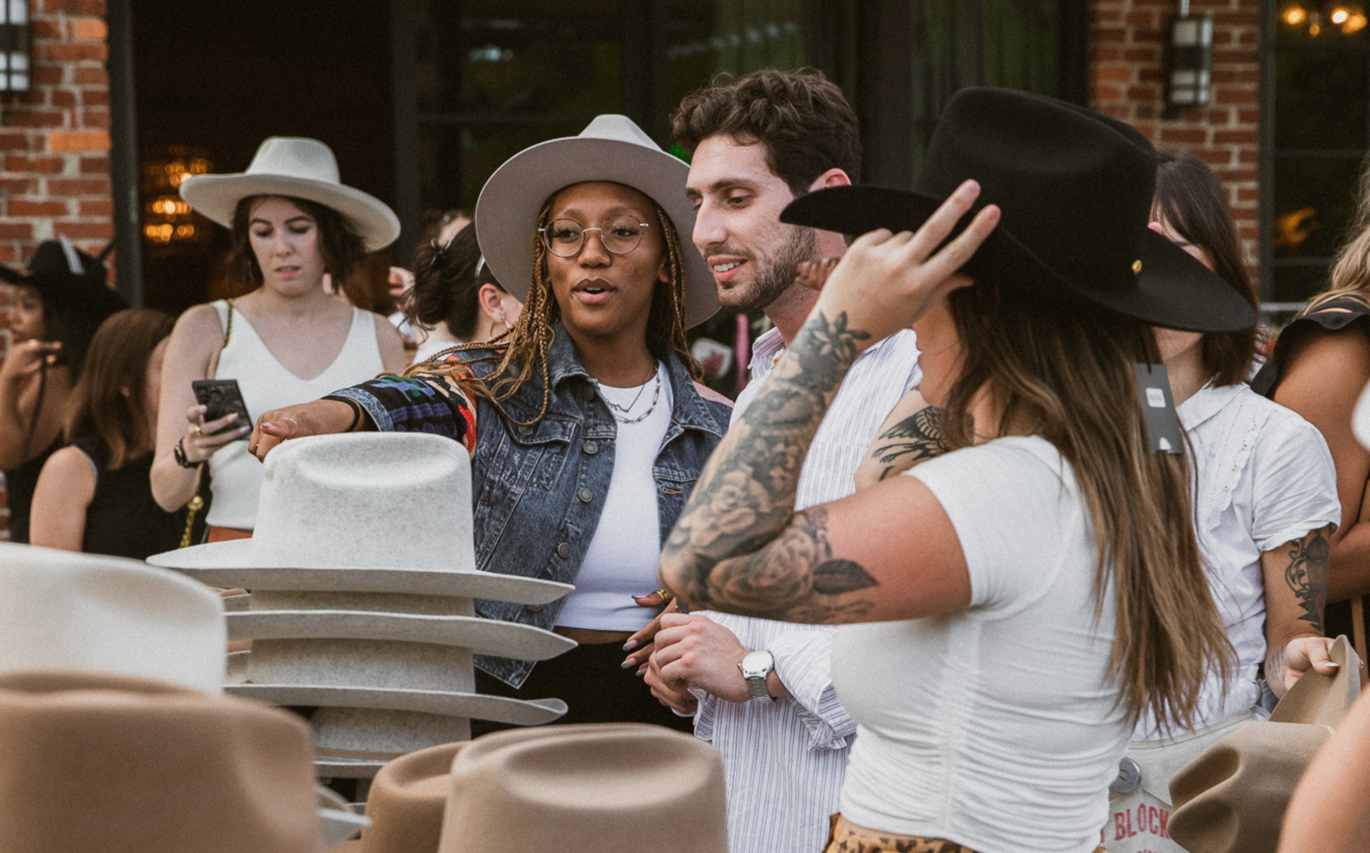 people happily shopping for classic western + trending hats at an event