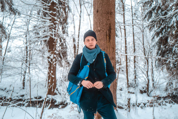 Junger Mann mit unisex Dreieckstuch im verschneitem Wald
