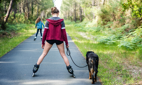 Female rollerblading with her dog on a street