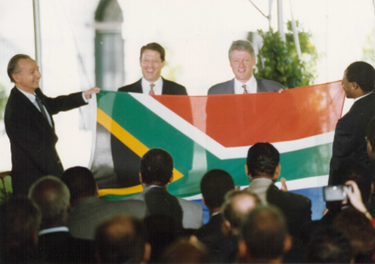 South African Ambassador to the U.S. Harry Schwarz presenting the new flag to the U.S. president Bill Clinton and vice president Al Gore in May 1994.