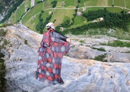 Wingsuit BASE jumping in red squirrel suit next to cliff above lauterbrunnen valley in switzerland