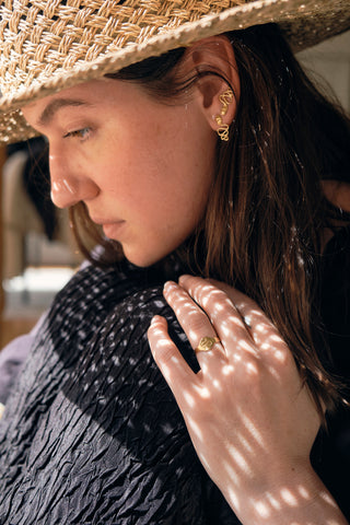 Model in sun hat wearing serpent jewellery