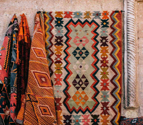 colorful, patterned rugs hanging against a wall.