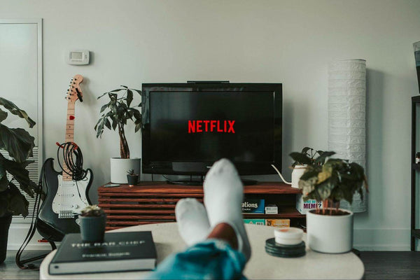 Feet on a coffee table with netflix on a TV screen