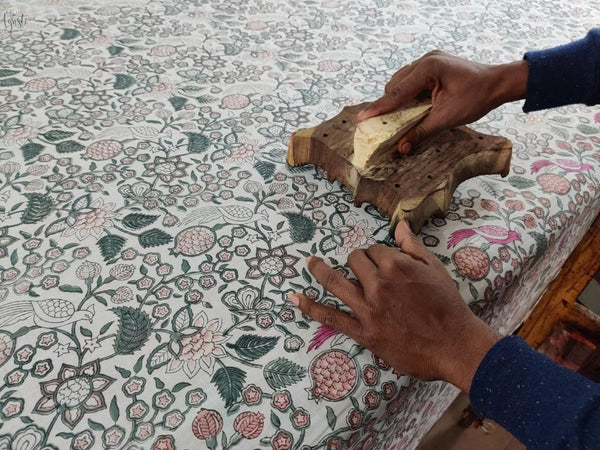 Artisan printing designs on a fabric using a wood carved with beautiful designs. This technique is called hand block printing. 