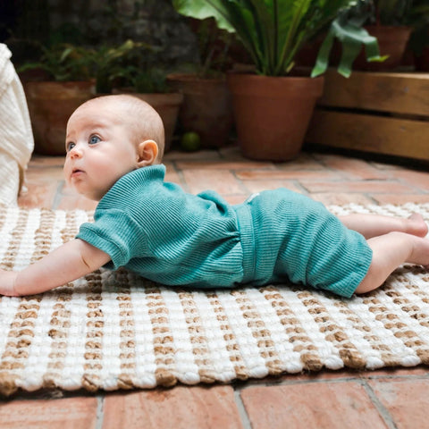 bebé tumbado en manta con conjunto verde