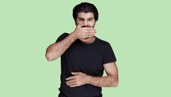 brown-haired man in black t-shirt hiding mouth on green background