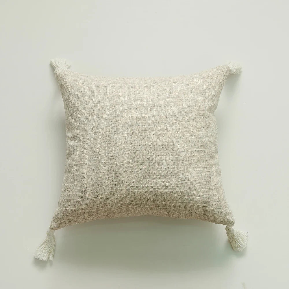  Beige colored woven handmade cotton throw pillow cover with tassels at each corner, displayed against a white background. 44583666319523