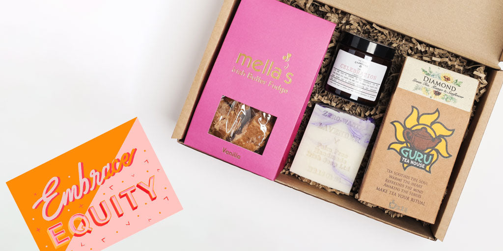 Overhead photo of a gift box for International Women's Day. Inside the box, there are four Irish-made products including a pink fudge pouch, a candle, a soap bar and tea.