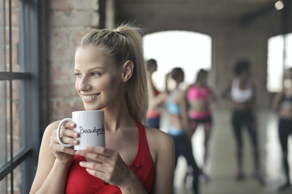 young woman drinking coffee in the gym