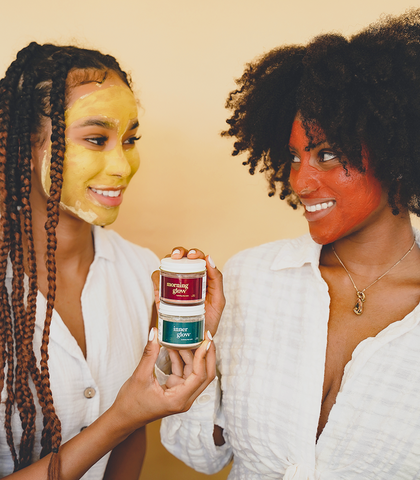 Two women looking at each other while holding and wearing Terra and Self clay masks