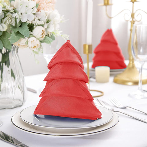 Christmas tree fold with a red linen napkin on plates at a holiday table setting