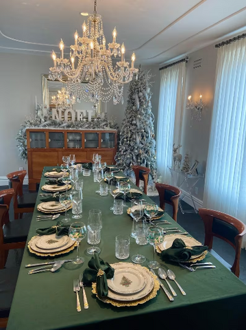holiday table settings for ten on a green velvet tablecloth in a formal dining room