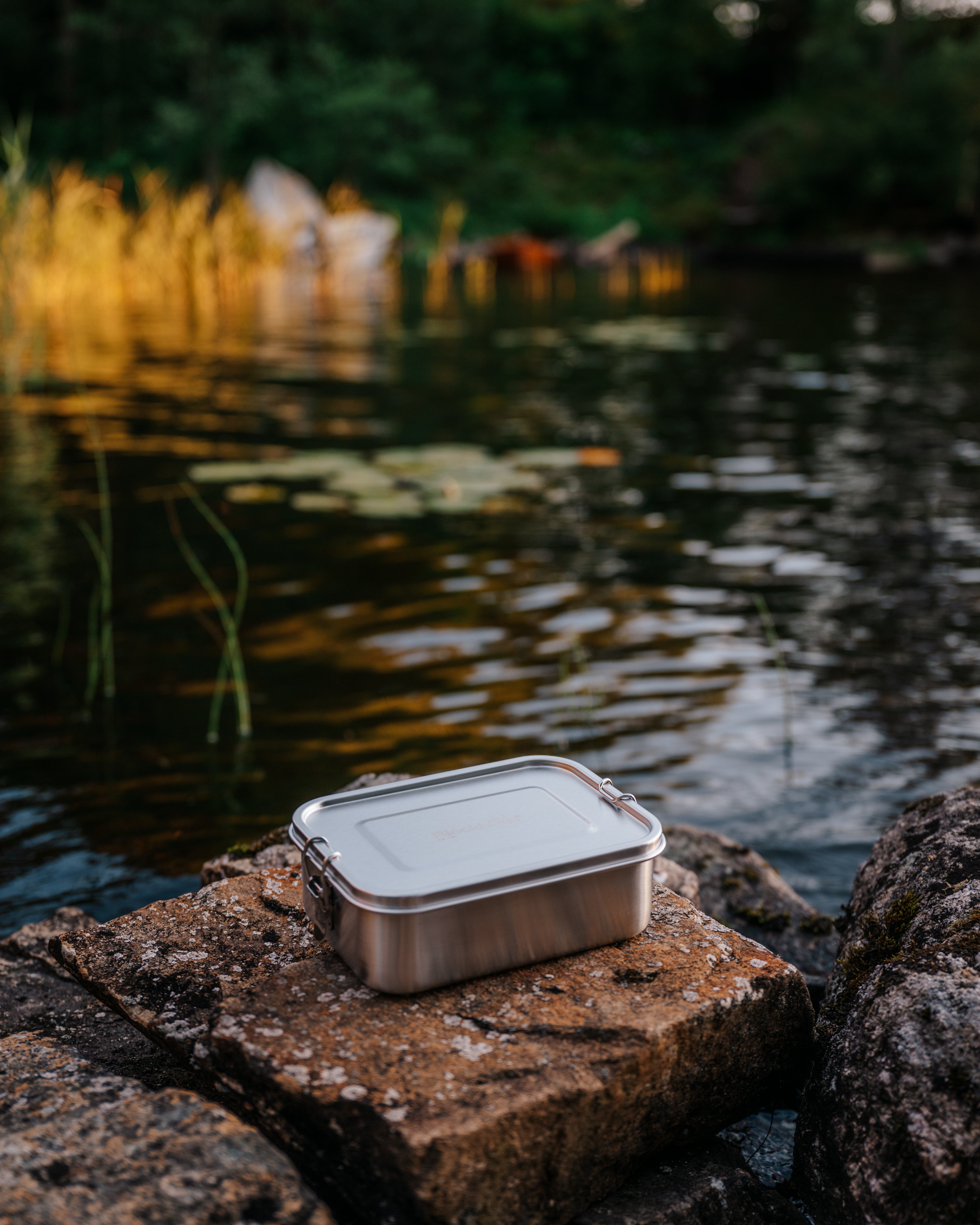 Blockhuette stainless steel lunch box on a rock infront of a lake