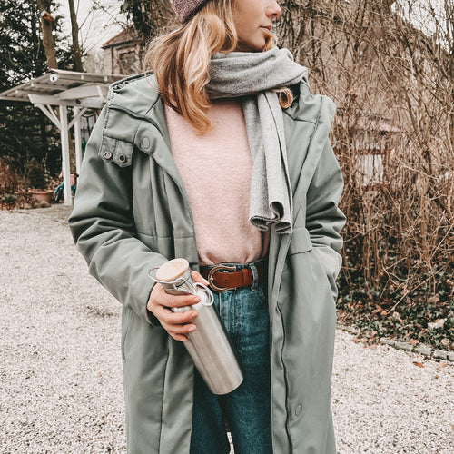 Frau mit roa Pullover hält Blockhütte Edelstahl Thermosflasche in der Hand