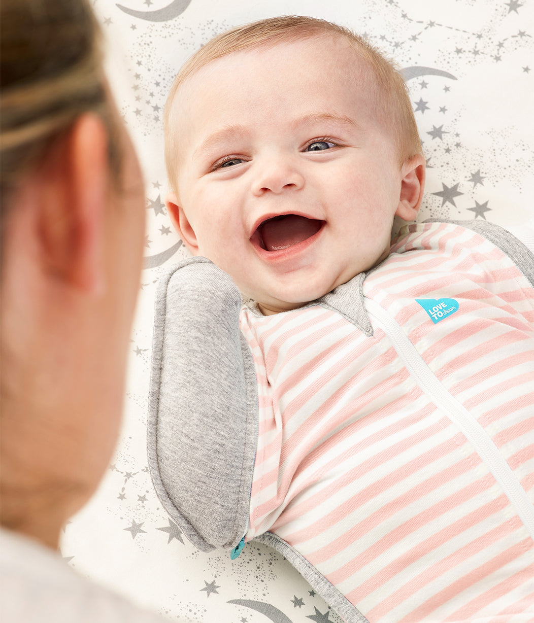 Mother with laughing baby wearing a transition swaddle